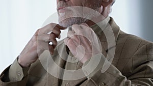 Elegant mature man putting vintage suit jacket on, preparing for date, fashion