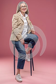 Elegant mature woman in beige jacket sitting on a chair