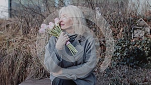 An elegant mature woman with flowers on the bench