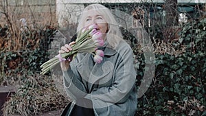 An elegant mature woman with flowers on the bench