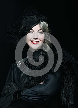 Elegant middle-aged woman in a black hat with a veil and a luxury dress.