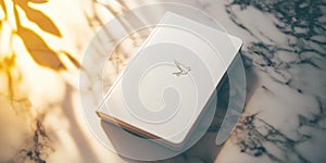Elegant minimalistic composition featuring a stylish white notebook with bird emblem on marble surface photo