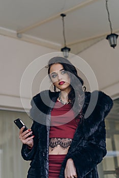 Elegant model in black coat with phone