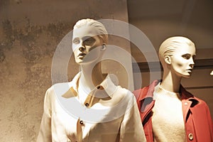 Elegant modern female mannequins in the showcase of a clothing store, warm gamma