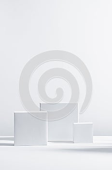 Elegant modern geometric style of showcase for cosmetics product display - white square podiums in sunlight with shadow in white.