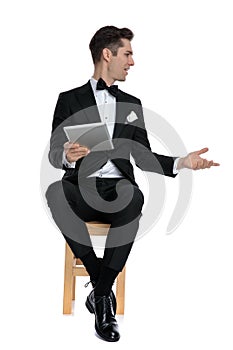 Elegant modern man in tuxedo holding tab and chatting