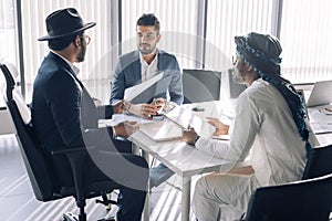 Elegant multiracial businessmen in suits gathered together for negotiating