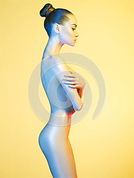 Elegant nude model in the light colored spotlights