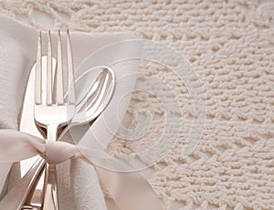 Elegant off white table place setting with silverware of fork, spoon and knife on cream cloth napkin and table cloth with room or