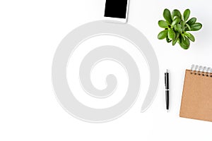 Elegant office desktop with smartphone, notebook, pen and small plant isolated on white background with copyspace.