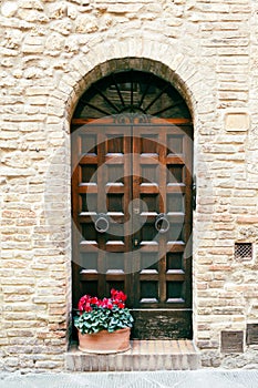 Elegant old double door entrance of building in Europe. Vintage wooden doorway of ancient stone house with a pot of