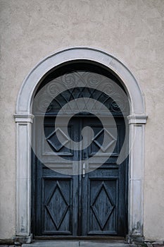 Elegant old double door entrance of building in Europe. Vintage wooden doorway and stucco fretwork wall of ancient stone