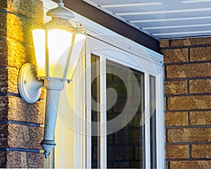 Elegant ornate porch light glowing by front door, welcoming