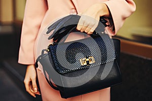 Elegant outfit. Closeup of black leather bag handbag in hand stylish woman. Fashionable girl on the street. Female