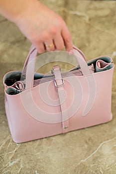 Elegant outfit. Closeup of pink powdery leather bag handbag in hand of stylish woman fashionable girl. Female fashion.