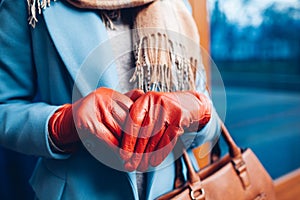 Elegant outfit. Closeup of of stylish woman in coat, scarf and brown gloves. Fashionable girl on the street.