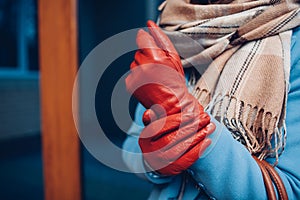 Elegant outfit. Closeup of of stylish woman in coat, scarf and brown gloves. Fashionable girl on the street.