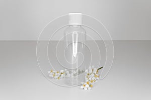 Elegant plastic cosmetic bottle without branding with white cherry blossoms on white background