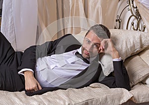 Elegant playboy reclining on a bed