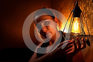 Elegant pretty middle aged woman with nice lamp at the dark room