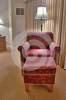 Elegant red armchair and pouffe on carpet