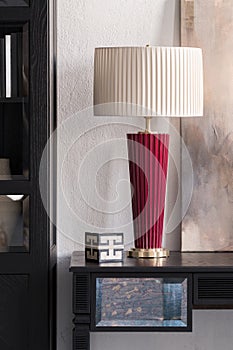 Elegant red and beige lamp on black desk, close-up