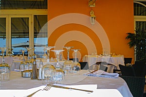 Elegant restaurant on French Riviera is waiting for guests, served dinner table with glasses, tableware and white linnen napkins