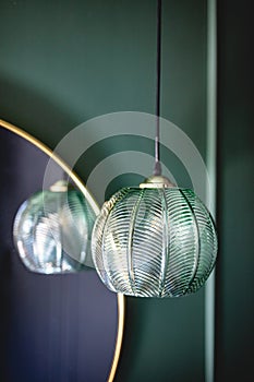 Elegant retro lamp hanging next to a mirror on dark green wall