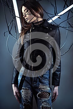 Elegant robot girl in wires in style cyberpunk in leather jacket and ripped jeans