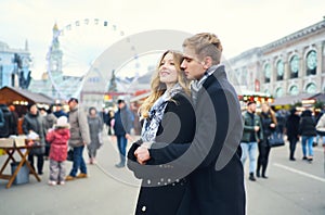 Elegant romantic couple in love hugging and kissing on street with attraction on background.