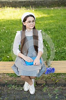 Elegant schoolgirl child girl with book in park, homework concept