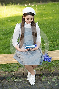 Elegant schoolgirl child girl with book in park, reading poetry concept