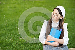 Elegant schoolgirl child girl reading book in park, poetry writer concept