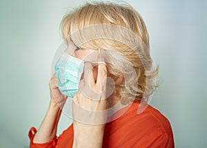Elegant senior woman putting properly surgical mask photo