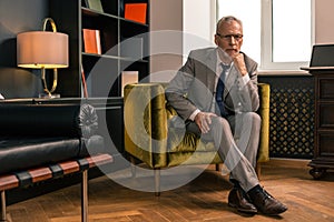 Elegant serious senior man sitting in his office