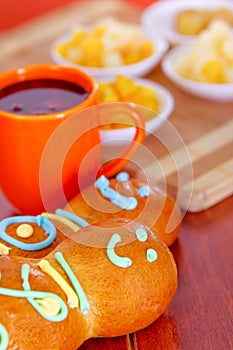 Elegant setup traditional tasty latin american guagua breads, colorful sugar decorations, orange cup with colada morada