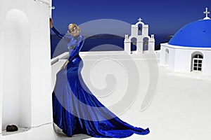 Elegant sexy female model in a blue long evening dress sensually poses against the background of the fabulous landscape of the