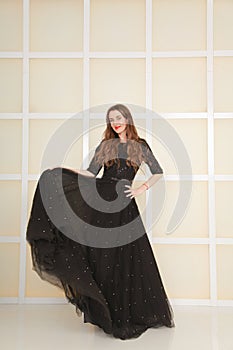 Elegant slim adult woman in fashion long evening lace black dress on white studio background, full length body