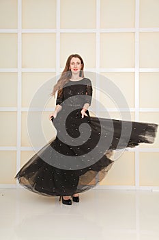Elegant slim adult woman in fashion long evening lace black dress on white studio background, full length body