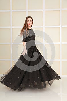 Elegant slim adult woman in fashion long evening lace black dress on white studio background, full length body