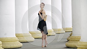 Elegant slim Caucasian woman standing on tiptoes holding pointes on shoulder. Portrait of beautiful ballet dancer in