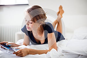 Elegant, smart, young woman using her tablet computer in bed