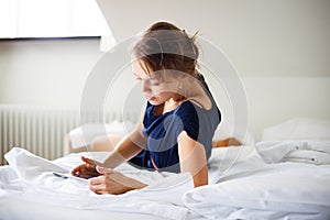 Elegant, smart, young woman using her tablet computer in bed