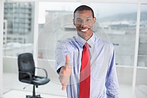 Elegant smiling Afro businessman offering handshake at office