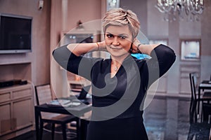 Elegant smiling woman is trying on beautiful necklace for in posh jewellery shop photo