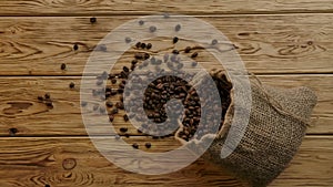 Elegant smoothly scattering roasted coffee beans from falling authentic jute bag . Slow motion