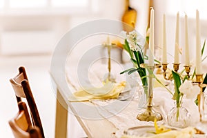 Elegant spring table setting with candles and flowers in a sunlit dining room