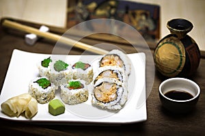 An elegant square white plate with fresh, healthy gourmet maki sushi sliced rolls with wasabi, ginger and soy sauce