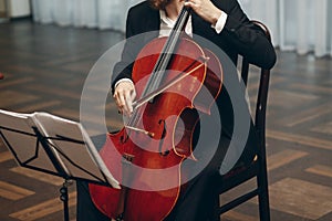 Elegant string quartet performing at wedding reception in restaurant, handsome man in suits playing violin and cello at theatre