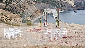 Elegant and stylish arch of the wedding ceremony on the beach. The wedding arch is decorated with a variety of flowers, chairs are
